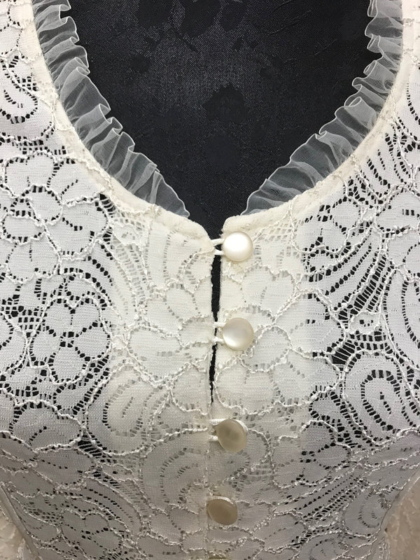 Detailaufnahme: Rüschen am Halsausschnitt und perlmuttartige Knöpfe der cremefarbenen Vintage-Spitzenjacke, feine florale Spitze