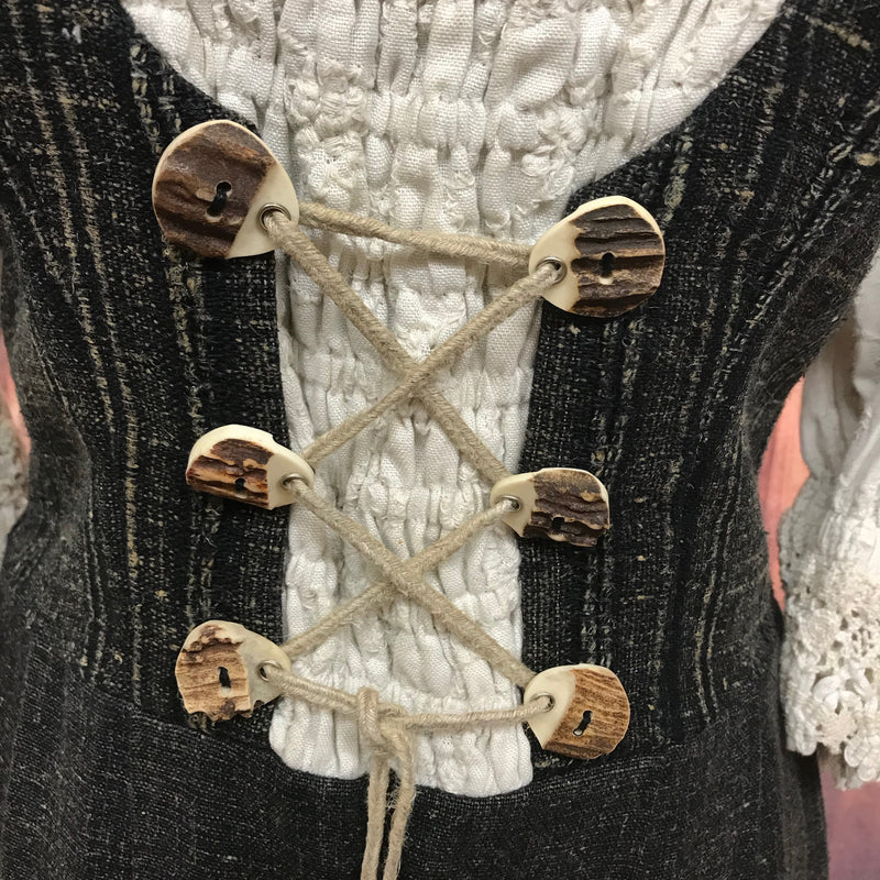 Detailaufnahme der Hornknöpfe mit Schnürung am Mieder des Trachtenkleids.